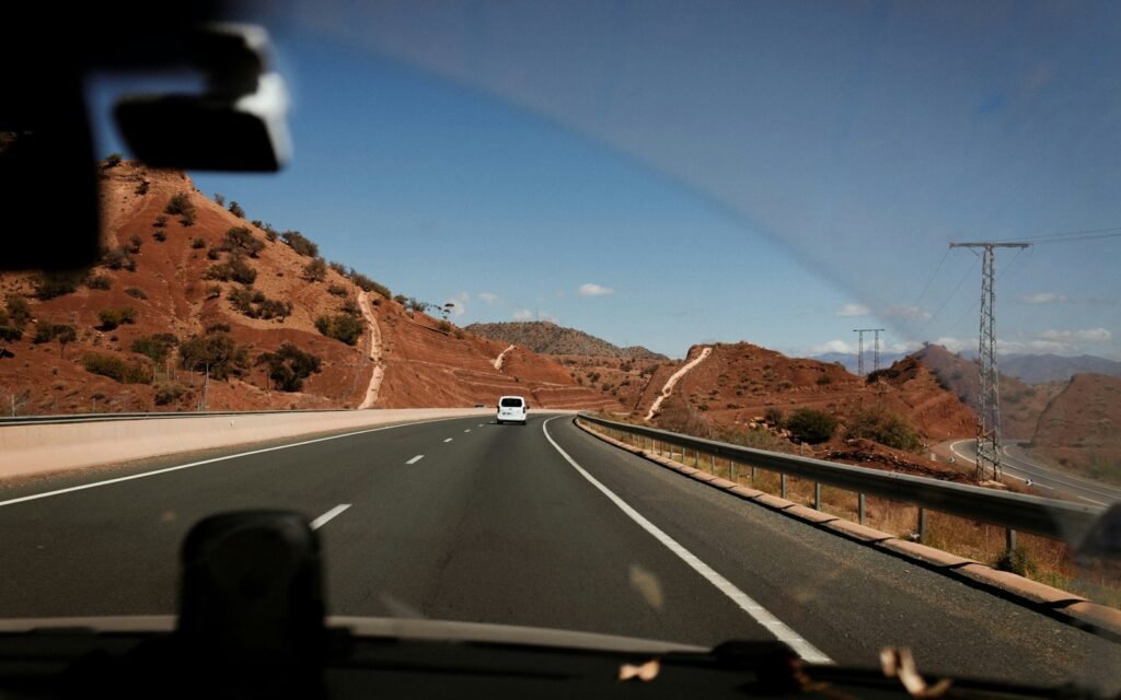 Road through red mountains seen from a car in Morocco